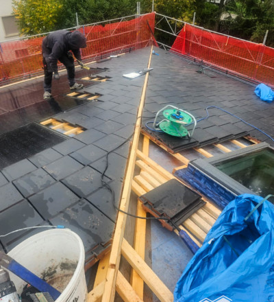 Ouvrier en pleine rénovation de la toiture et de la mise en place des photovoltaïques