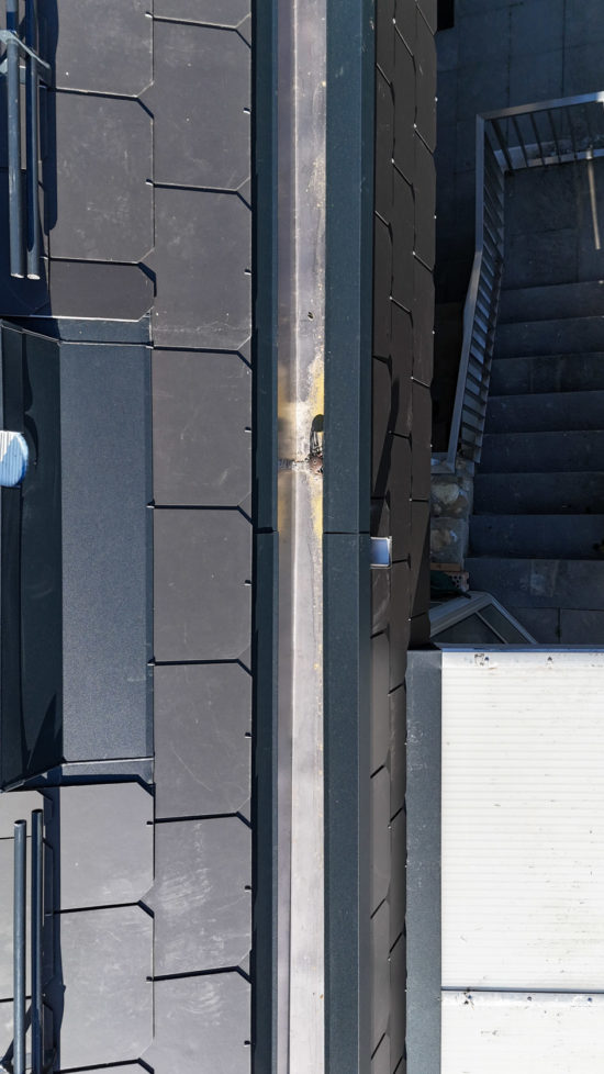 Installation de la gouttière d'un toit dans une maison à Genolier, Suisse