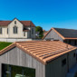 Vue sur les tuiles rénovées, l'installation du panneau solaire par Toiture Willy et de l'église du village de Mannens